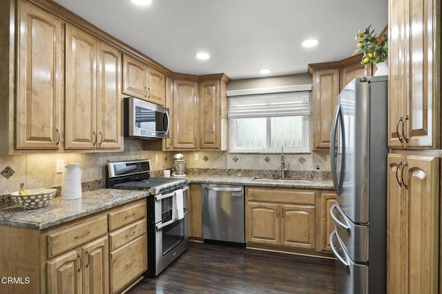 kitchen featuring sink, dark wood-type flooring, appliances with stainless steel finishes, backsplash, and light stone countertops