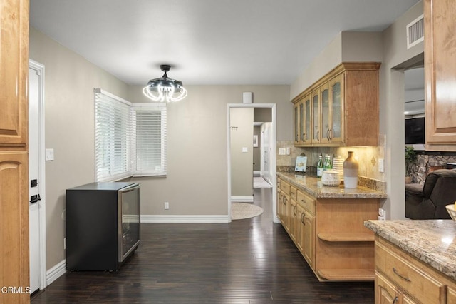 kitchen featuring light stone counters, decorative backsplash, dark wood-type flooring, and beverage cooler