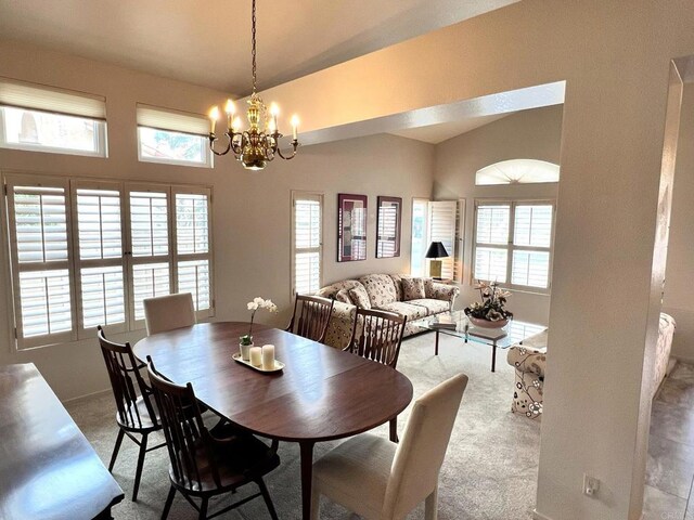 carpeted dining room with an inviting chandelier and vaulted ceiling