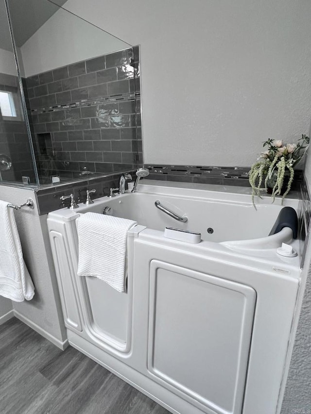 bathroom with hardwood / wood-style floors and a tub to relax in