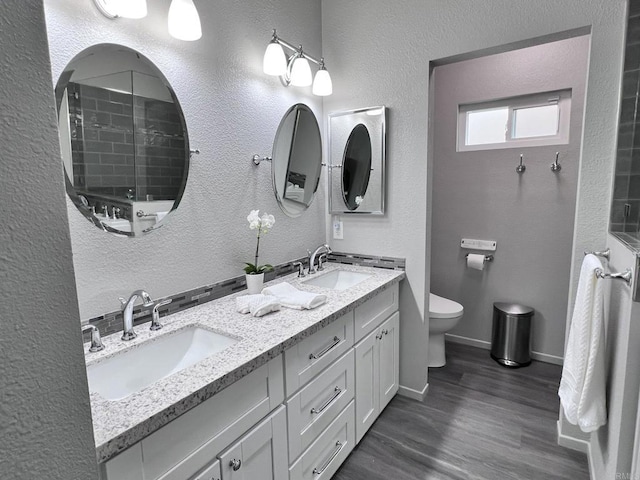 bathroom with wood-type flooring, walk in shower, vanity, and toilet