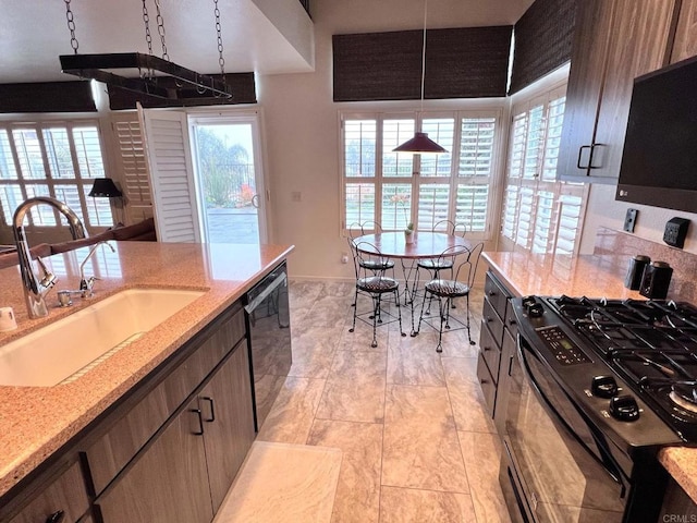 kitchen with pendant lighting, sink, black appliances, and light stone countertops