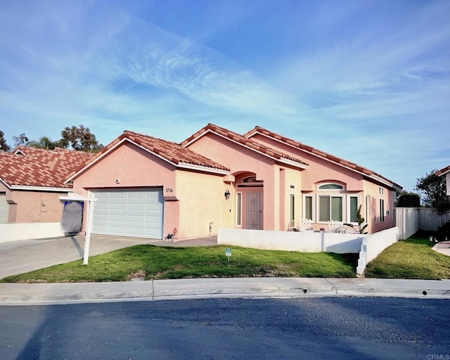 mediterranean / spanish-style home with a garage, concrete driveway, a tile roof, fence, and stucco siding