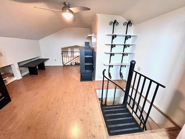 stairway featuring vaulted ceiling, a ceiling fan, and wood finished floors