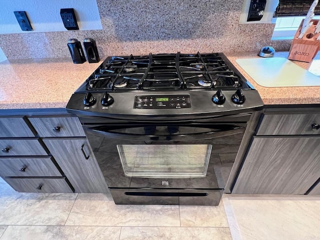 details with backsplash, black gas range oven, and light countertops