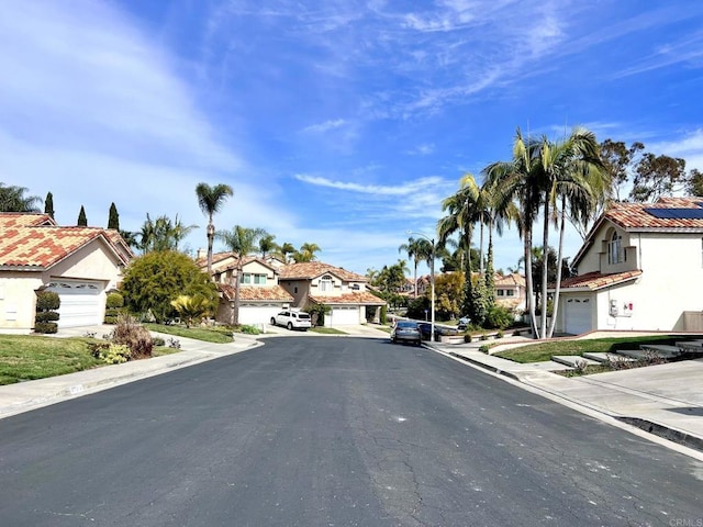 view of street with curbs, a residential view, street lighting, and sidewalks