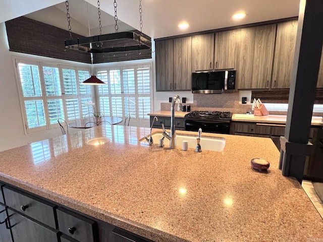 kitchen featuring stainless steel microwave, light stone counters, gas stove, and recessed lighting