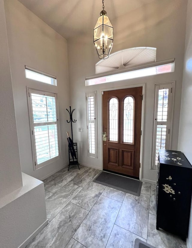 entryway with a high ceiling, baseboards, and a chandelier