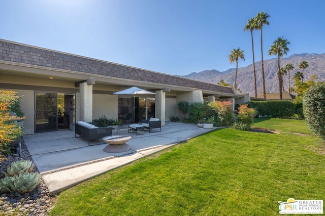 rear view of property with a mountain view, a lawn, and a patio