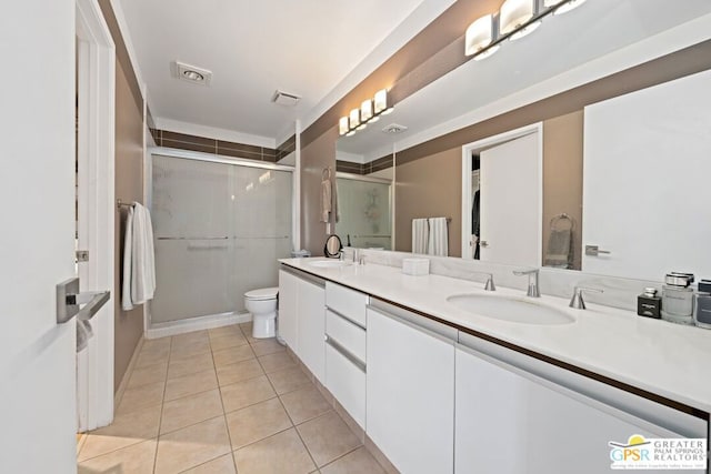 bathroom featuring tile patterned floors, toilet, a shower with door, and vanity