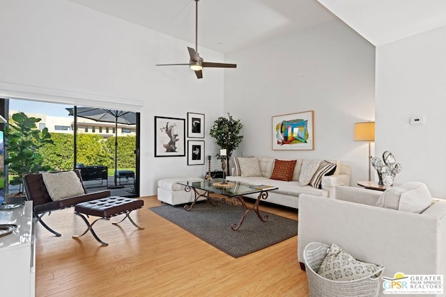 living room with ceiling fan, wood-type flooring, and a high ceiling