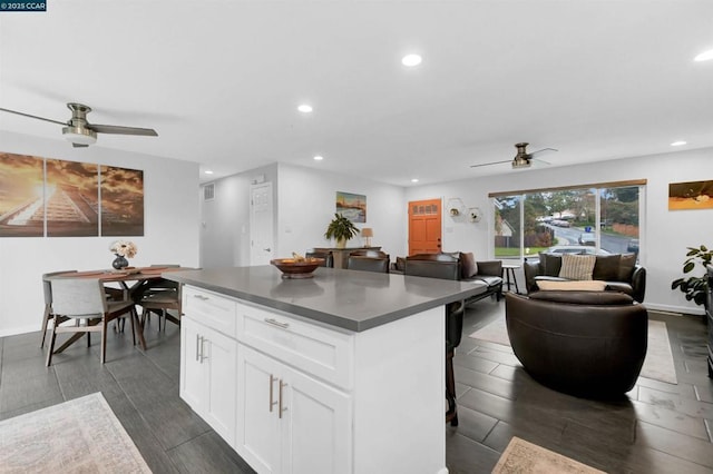 kitchen featuring white cabinetry, ceiling fan, a center island, and a breakfast bar area