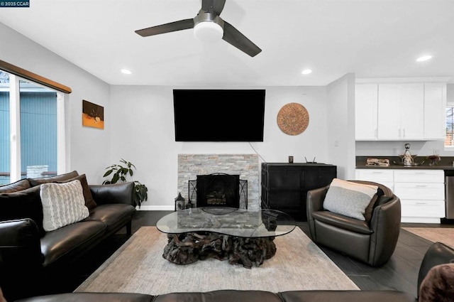 living room with a stone fireplace and ceiling fan