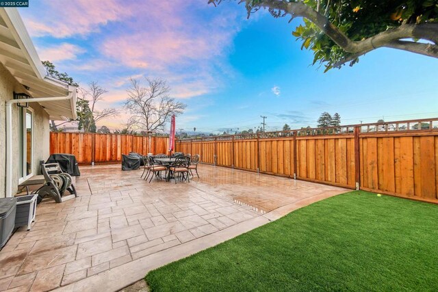 patio terrace at dusk featuring a yard