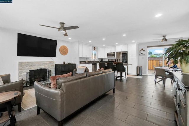 living room featuring a stone fireplace and ceiling fan