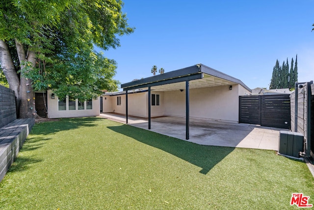 rear view of house featuring a lawn and a patio