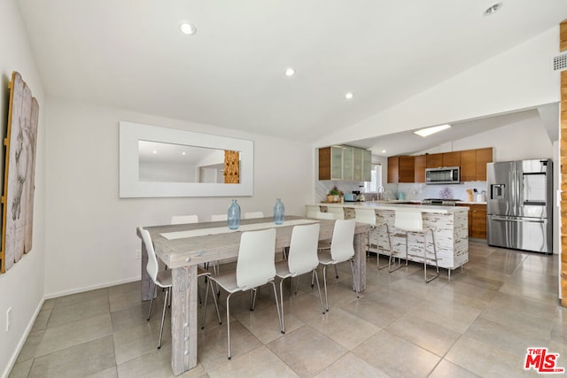 dining space with lofted ceiling, sink, and light tile patterned floors