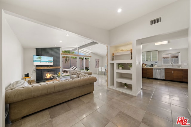 tiled living room with lofted ceiling with beams, a fireplace, and sink