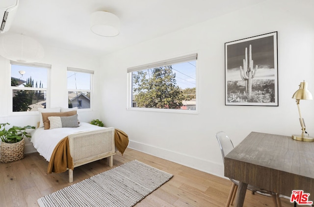 bedroom featuring wood-type flooring and a wall unit AC