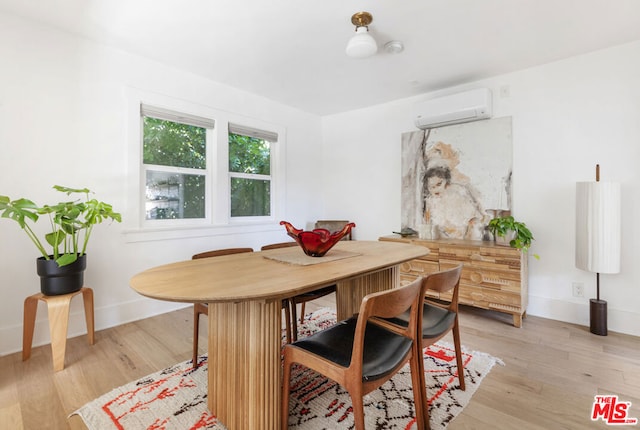 dining room featuring a wall mounted air conditioner and light hardwood / wood-style flooring