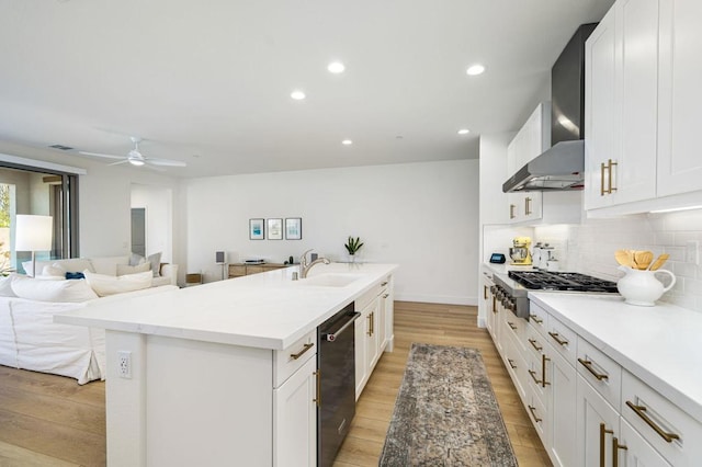 kitchen with a kitchen island with sink, wall chimney range hood, white cabinetry, and stainless steel appliances