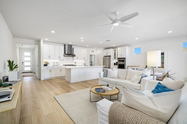 living room with ceiling fan, sink, and light hardwood / wood-style floors