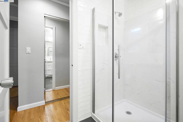 bathroom with a shower with door and hardwood / wood-style floors