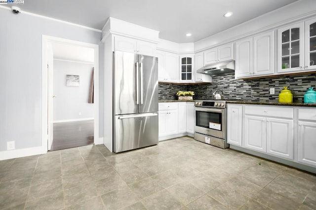 kitchen with stainless steel appliances, white cabinets, dark stone counters, and decorative backsplash