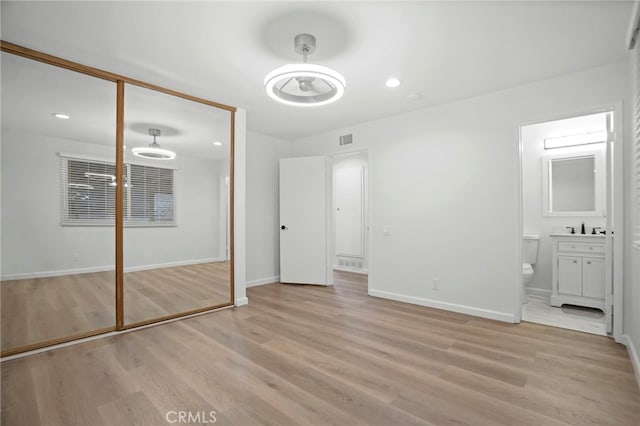 unfurnished bedroom with sink, a closet, and light wood-type flooring