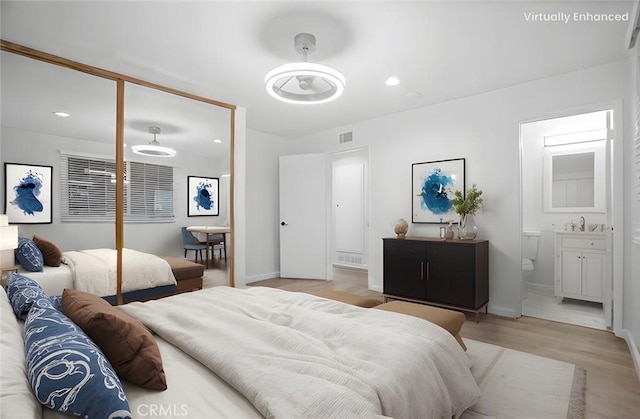 bedroom featuring sink, light hardwood / wood-style floors, and ensuite bath