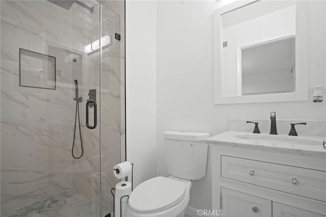 bathroom featuring vanity, a shower with shower door, and toilet