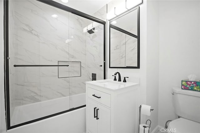 full bathroom featuring vanity, combined bath / shower with glass door, and toilet