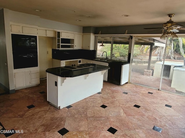 kitchen with a kitchen island, sink, a kitchen breakfast bar, ceiling fan, and black appliances