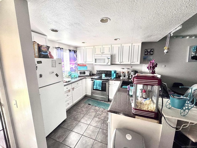 kitchen featuring white cabinetry, decorative light fixtures, dark tile patterned flooring, white appliances, and dark stone counters