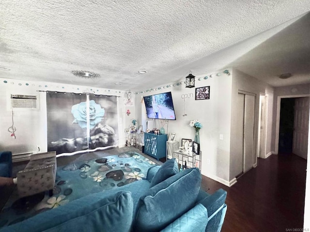 living room featuring a baseboard radiator, hardwood / wood-style floors, a wall unit AC, and a textured ceiling