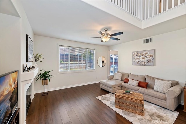 living room featuring dark wood-type flooring and ceiling fan