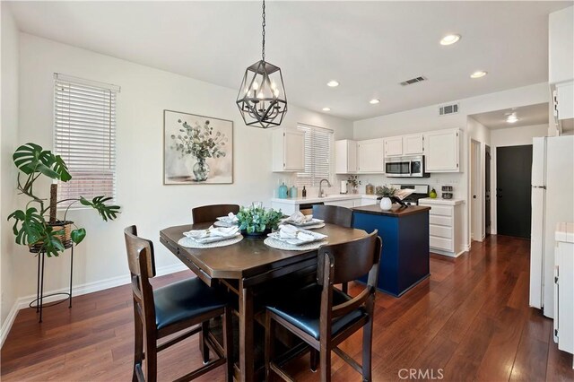 dining area featuring dark wood-type flooring, sink, and a notable chandelier