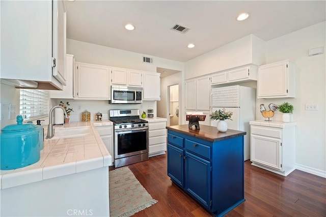 kitchen with blue cabinetry, appliances with stainless steel finishes, a center island, and white cabinets