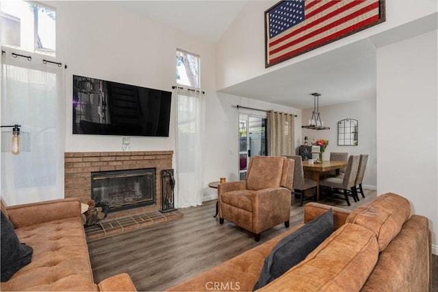 living room featuring a brick fireplace, hardwood / wood-style flooring, and high vaulted ceiling