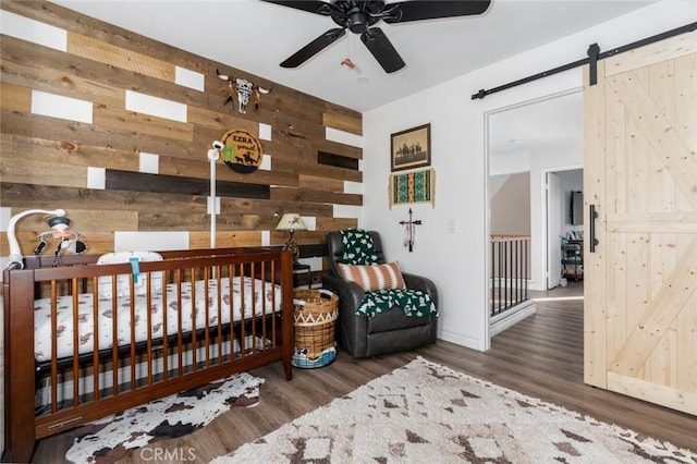 bedroom with dark hardwood / wood-style flooring, wooden walls, and a barn door