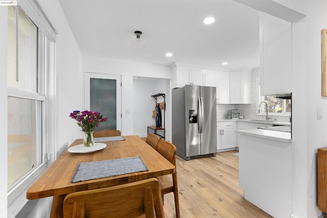 kitchen with sink, white cabinets, stainless steel fridge, decorative backsplash, and light hardwood / wood-style flooring