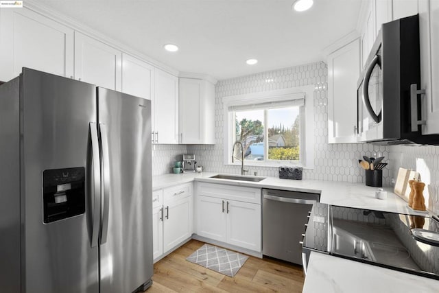 kitchen featuring white cabinetry, sink, stainless steel appliances, and light hardwood / wood-style floors