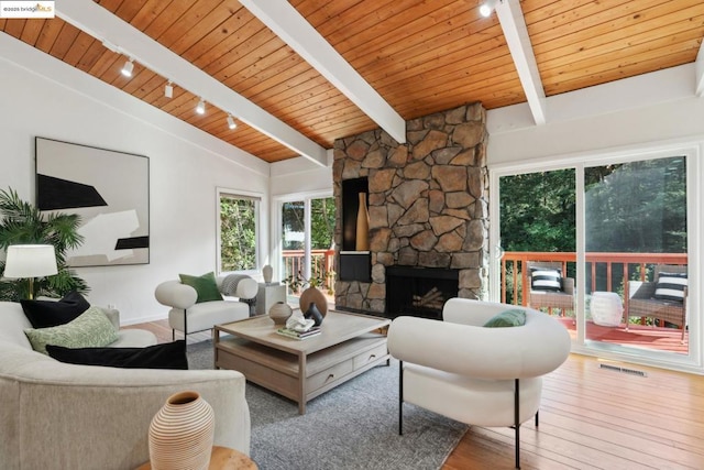 living room featuring lofted ceiling with beams, a stone fireplace, hardwood / wood-style floors, and wooden ceiling