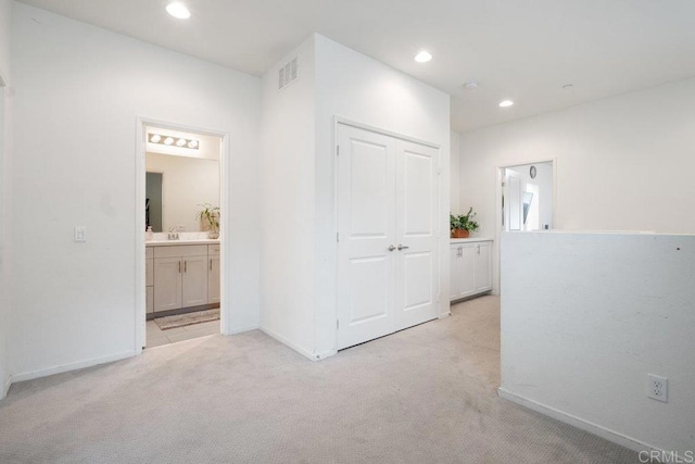 hall featuring sink and light colored carpet