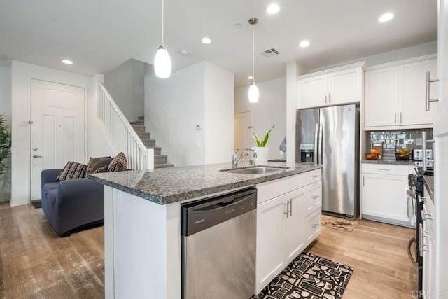 kitchen with sink, decorative light fixtures, a center island with sink, stainless steel appliances, and white cabinets