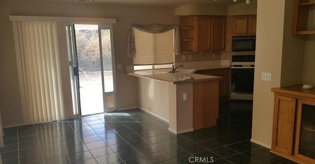 kitchen featuring dark tile patterned floors, sink, white range with electric stovetop, and kitchen peninsula