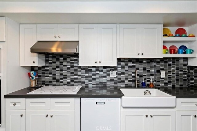 kitchen with extractor fan, white appliances, white cabinets, and backsplash