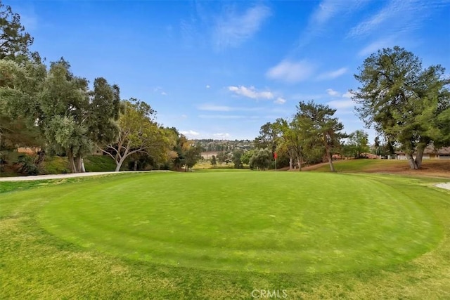 view of property's community featuring view of golf course and a lawn