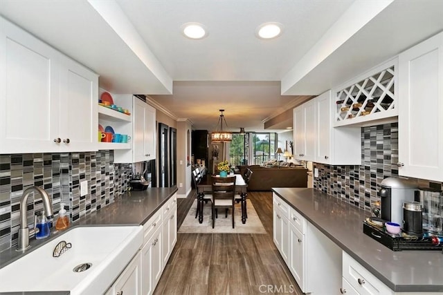 kitchen with sink, decorative light fixtures, dark hardwood / wood-style floors, white cabinets, and backsplash