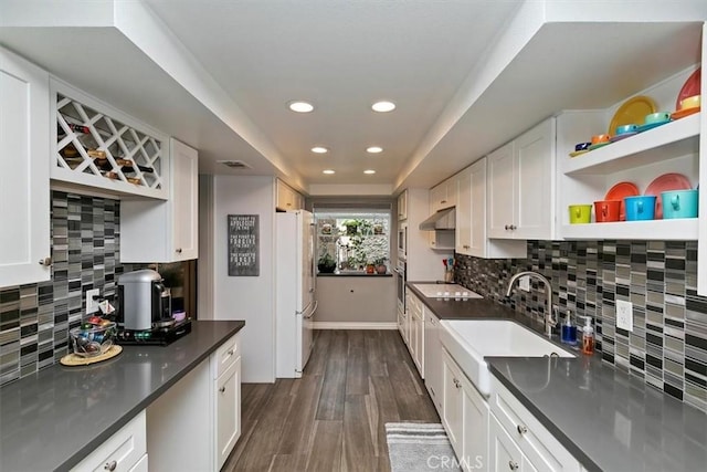 kitchen with dark countertops, white cabinets, under cabinet range hood, and open shelves